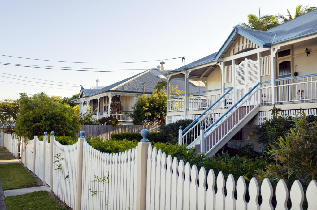 traditional queenslander shown with cream colonial fence and front garden