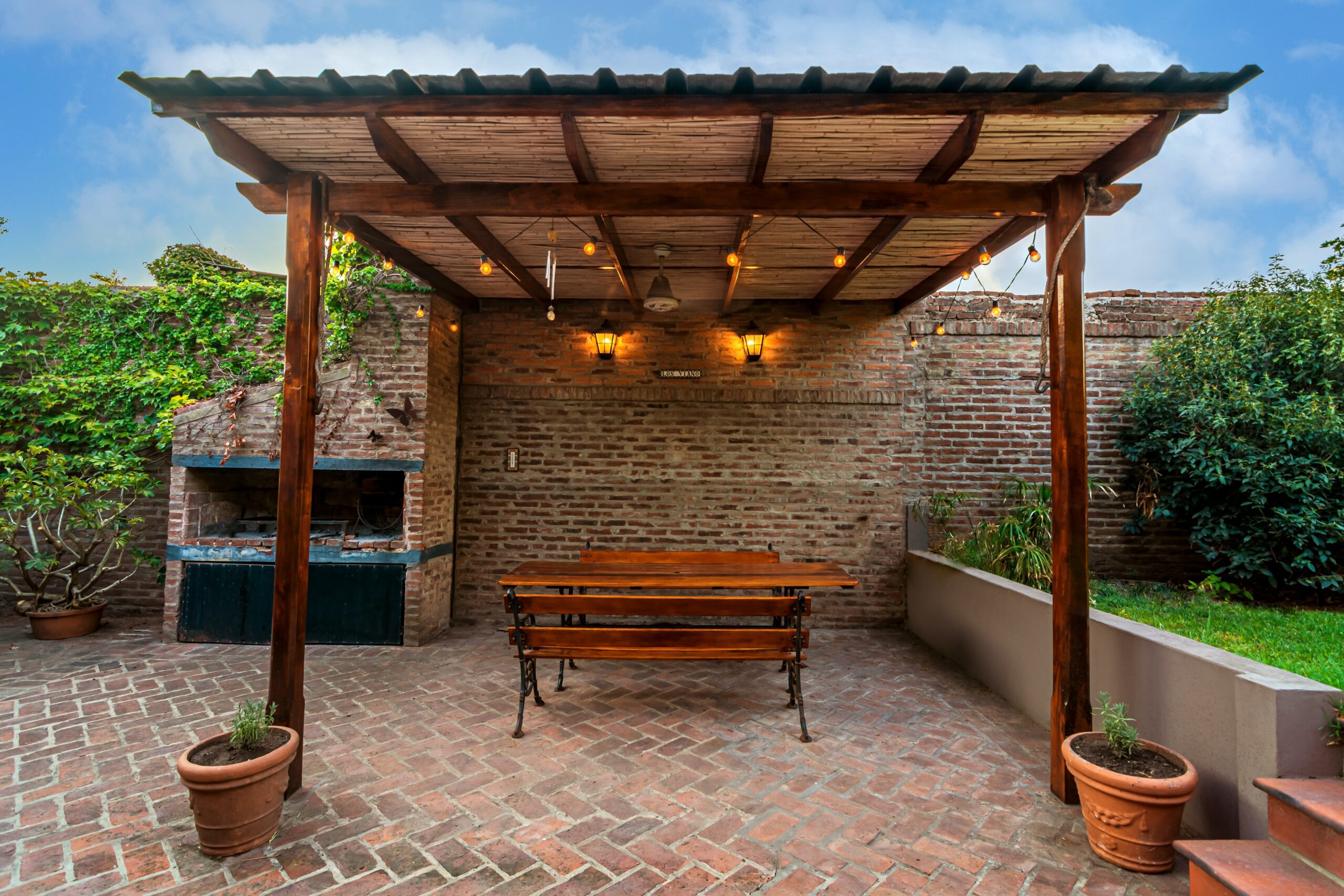 timber pergola in backyard with tall brick wall behind