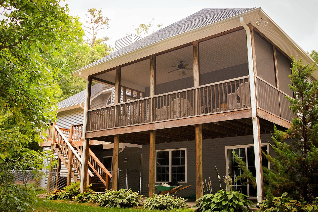 backyard timber porch and deck. the verandah is enclosed and there and trees and plants in the garden.