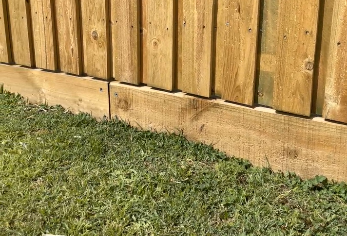 Pine sleeper used as fence plinth under lapped pine fence palings.
