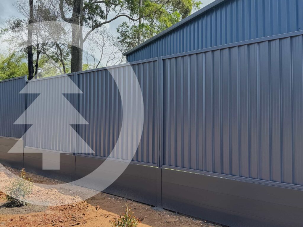 Colorbond fence in colour ironstone which appears as a navy blue in backyard with dirt below and trees in background. A transparent Narangba timbers logo covers the left portion of image