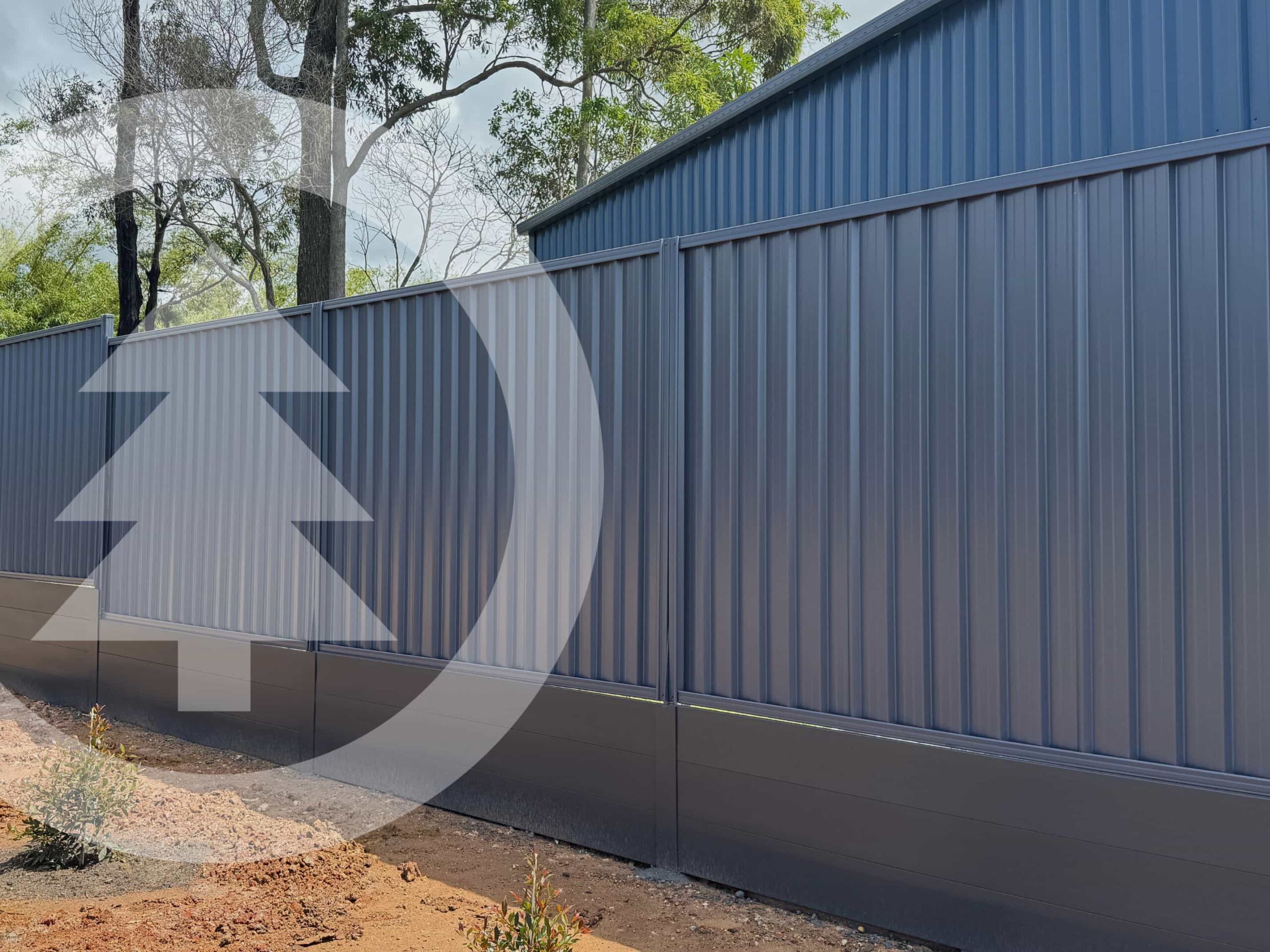 Colorbond fence in colour ironstone which appears as a navy blue in backyard with dirt below and trees in background. A transparent Narangba timbers logo covers the left portion of image