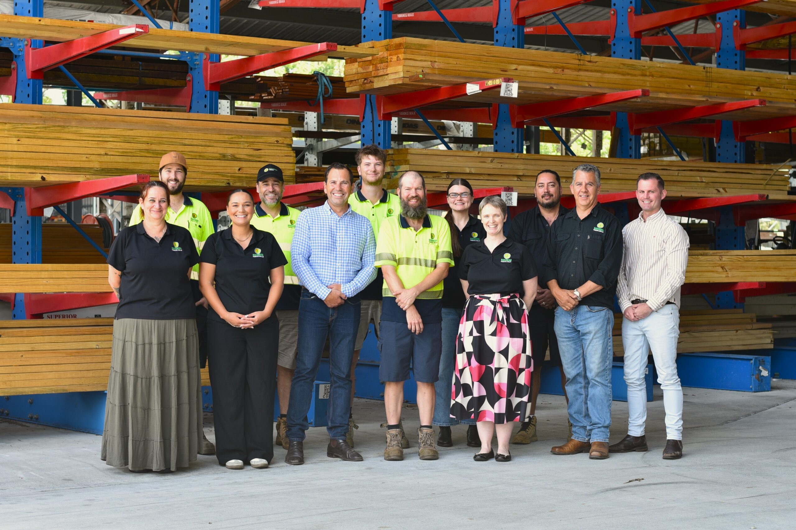 group portrait showing 12 people standing side-by-side. A mix of men and women wearing a variety of professional clothes and high visibility construction gear